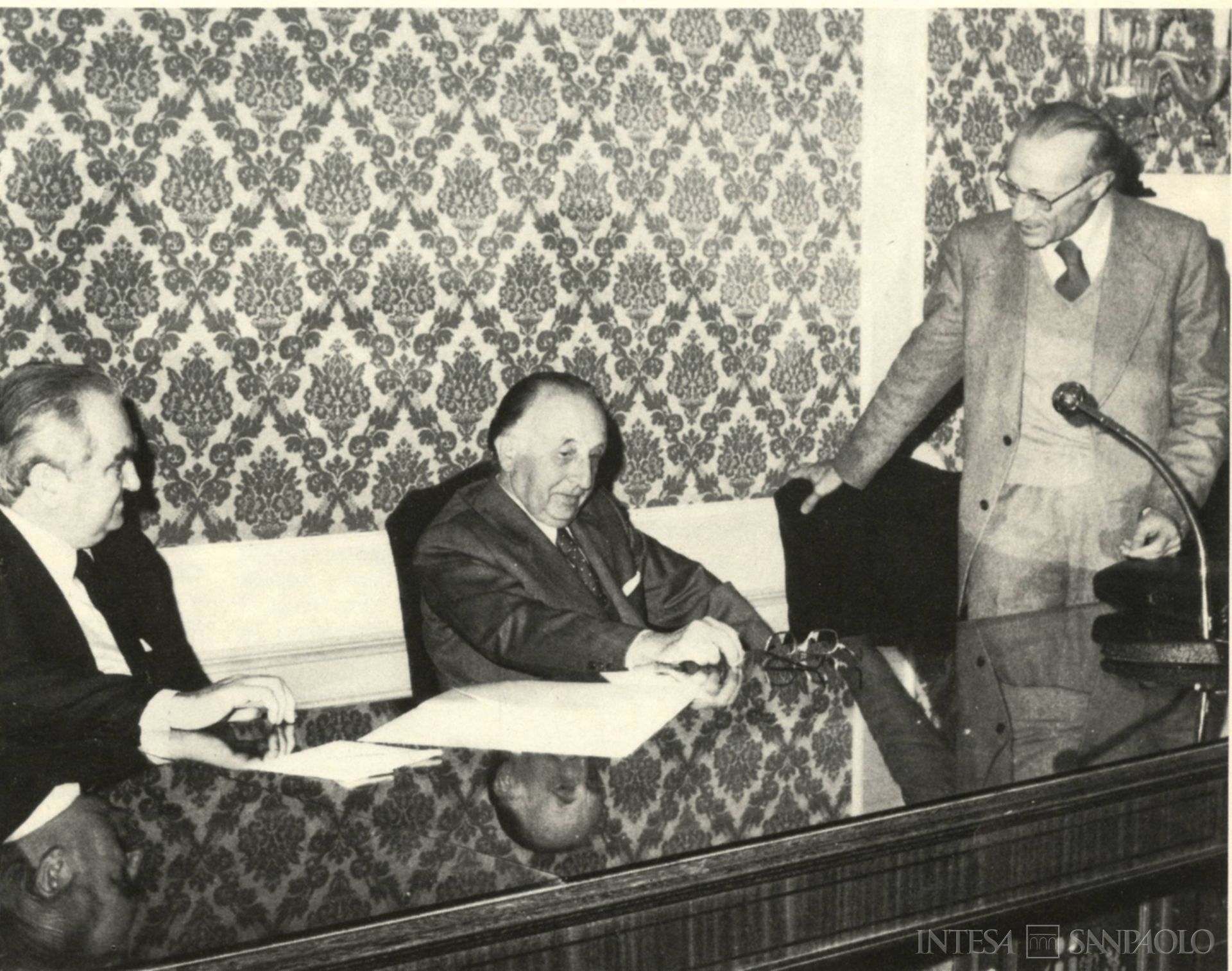 Cassa di Risparmio di Foligno, il direttore generale Leonello Radi, il professor Tucci dell'Università di Roma e il presidente della Cassa Giuseppe Mancini durante un seminario sul commercio estero, fotografia tratta da Il Bollettino del Risparmio, n. 1, 1977 (fotografo sconosciuto)