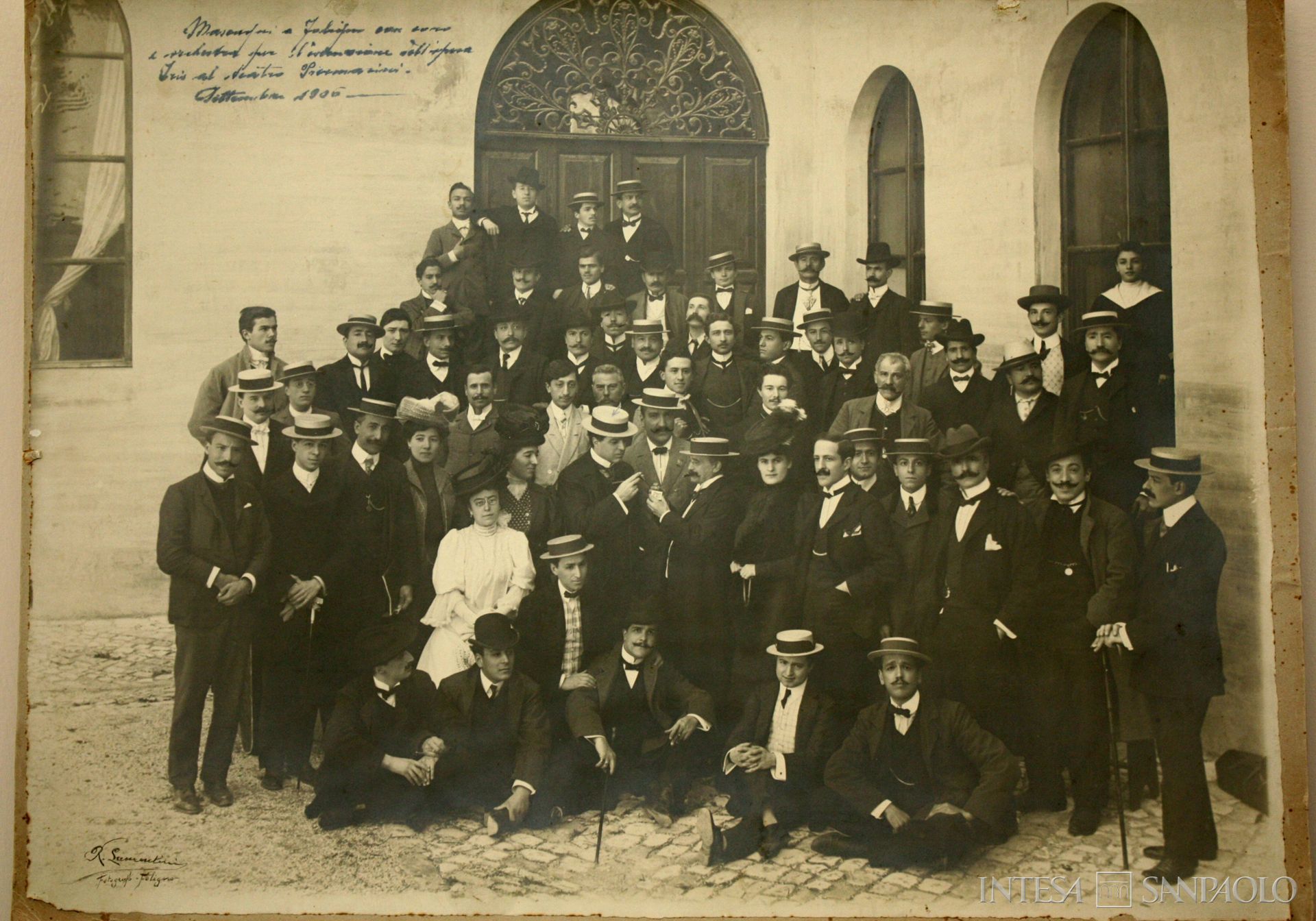 Cassa di Risparmio di Foligno, il maestro Pietro Mascagni a Foligno fra i componenti del coro e dell'orchestra per la rappresentazione dell'opera Iris; all'evento assisterono senatori e deputati delle regioni umbre, laziali e marchigiane, responsabili delle Camere di Commercio, industriali e commercianti, invitati dal direttore generale della Cassa, nonché sindaco di Foligno, Arturo Buffetti Berardi per un incontro finalizzato alla promozione dello sviluppo economico e sociale dell'area centrale del Paese, settembre 1906 (fotografo Rinaldo Laurentini)